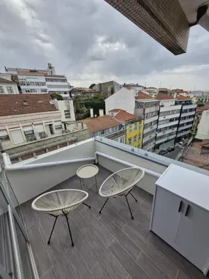 a balcony with two chairs and tables on a building at Essence Santa Catarina Flat in Porto