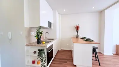 a kitchen with white cabinets and a counter top at Essence Santa Catarina Flat in Porto