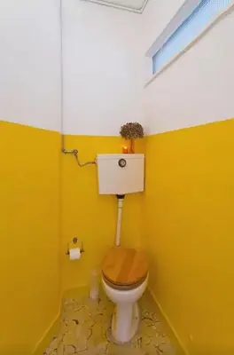 a bathroom with a toilet with a yellow wall at PinPorto City Center I in Porto
