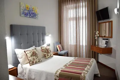 a hotel room with a bed and a window at Lusitana Hotel in Porto