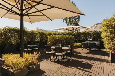 a patio with tables and chairs and an umbrella at Timbre Heroismo in Porto