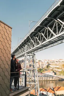 two people standing on a balcony under a bridge at Oh! Porto Apartments in Vila Nova de Gaia