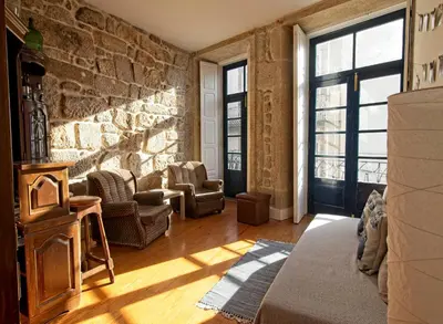 a living room with chairs and a stone wall at Ribeira Smart Flat in Porto