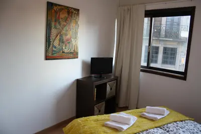 a bedroom with a bed and a tv and a window at Alegria Rooms in Porto