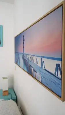 a tv hanging on a wall with a picture of a lighthouse at Ribeira Smart Suite in Porto
