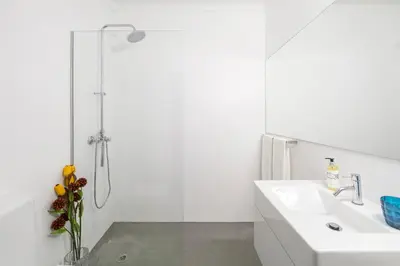 a white bathroom with a shower and a sink at CdC Apartments by Casa do Conto in Porto