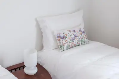 a white bed with a pillow and a vase on a table at CdC Apartments by Casa do Conto in Porto