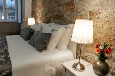 a bedroom with a bed with pillows and a table with a lamp at Authentic Porto Apartments in Porto