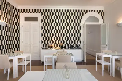 a restaurant with white tables and chairs and a black and white wall at Oporto Comfort Charming Cedofeita - Free Parking in Porto