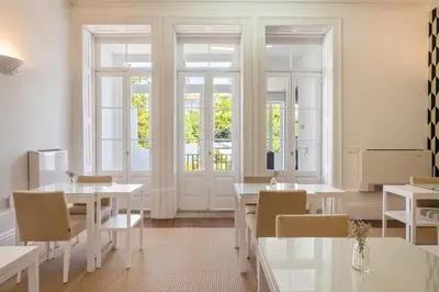 a dining room with white tables and chairs and windows at Oporto Comfort Charming Cedofeita - Free Parking in Porto