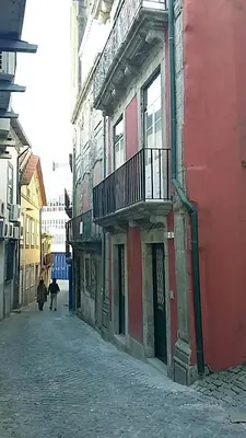 an alley with a red building with a balcony at Casa do Cristelo in Porto