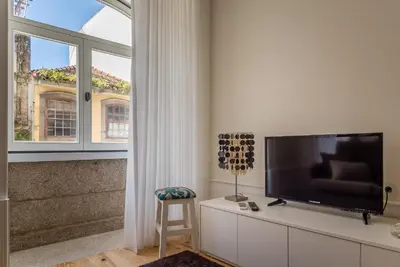a living room with a flat screen tv and a chair at Casa d'Alma by Oporto Soul in Porto