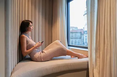 a woman sitting on a window sill looking out the window at PortoBay Teatro in Porto