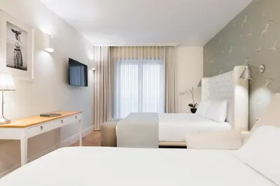 a white hotel room with two beds and a desk at Eurostars Porto Douro in Porto