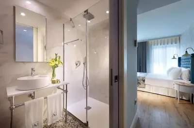 a bathroom with a shower and a sink and a bed at Eurostars Porto Douro in Porto