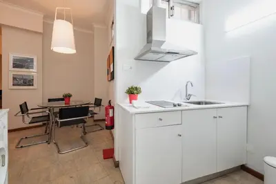 a kitchen with white cabinets and a table with chairs at BmyGuest - Santa Catarina Downtown Apartment in Porto