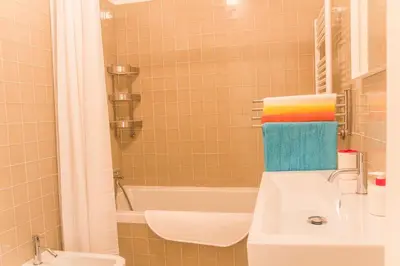 a bathroom with a sink and a bath tub with towels at BmyGuest - Cardosas Stylish Apartment in Porto