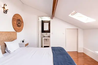 a bedroom with a white bed and a bathroom at VIVA Almada Flats in Porto