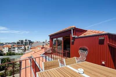 a red house with a deck with chairs on it at Oporto Maison Alves da Veiga in Porto