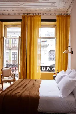 a bedroom with a bed and a window with yellow curtains at Cocorico Luxury House - Porto in Porto