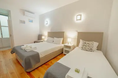 two beds in a room with white walls and wooden floors at Dear Porto By Hosty in Porto