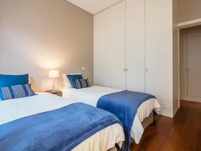 a bedroom with two beds with blue and white sheets at Cardosas Boutique Apartment in Porto