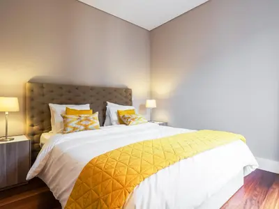 a bedroom with a large bed with yellow pillows at Cardosas Boutique Apartment in Porto