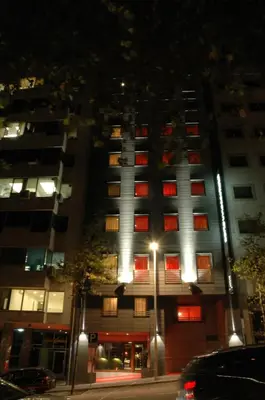 a tall building with red windows at night at Porto Trindade Hotel in Porto