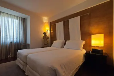 a hotel room with a large white bed with a window at Porto Trindade Hotel in Porto