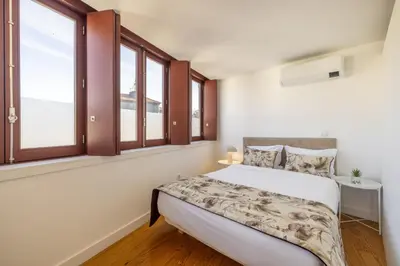 a bedroom with a bed and two windows at Try Oporto - São Lázaro in Porto