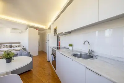 a kitchen with a sink and a living room at Try Oporto - São Lázaro in Porto