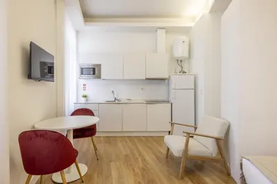 a kitchen with a table and chairs and a refrigerator at Try Oporto - São Lázaro in Porto