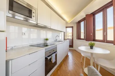 a kitchen with white cabinets and a sink and a table at Try Oporto - São Lázaro in Porto