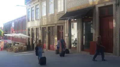 a group of people walking down a street with luggage at Apartamento LM Ribeira in Porto