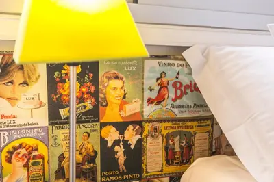 a table with a lamp and a bunch of movie posters at Apartamento Vintage 2 in Porto