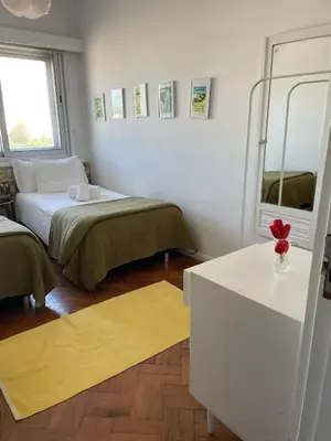 a room with two beds and a table and a mirror at Apartamento Vintage 2 in Porto