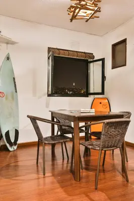 a dining room with a table and a surfboard on a wall at Douro Surf Hostel in Vila Nova de Gaia