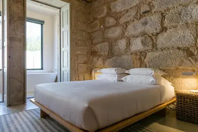 a bedroom with a stone wall and a bed with pillows at Armazém Luxury Housing- Architectural & Design Hotel in Porto