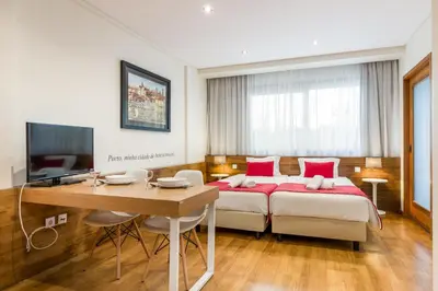 a bedroom with a bed and a desk and a television at BRA.com Apartments Oporto Bonfim in Porto
