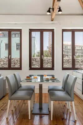 a dining room with a table and chairs and windows at BRA.com Apartments Oporto Pinheiros in Porto