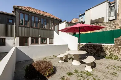 a patio with a table and a red umbrella at BRA.com Apartments Oporto Pinheiros in Porto