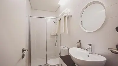 a white bathroom with a sink and a shower at BmyGuest - Almada Garden Apartment in Porto