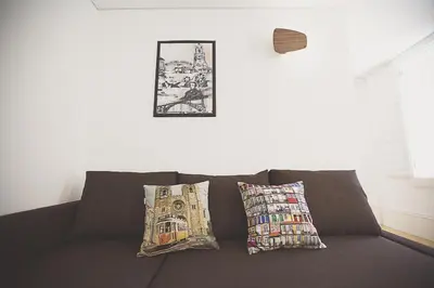 a couch with two pillows and a picture on the wall at BmyGuest - Almada Garden Apartment in Porto