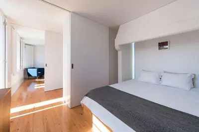 a bedroom with a white bed and a wooden floor at BmyGuest - Almada Garden Apartment in Porto