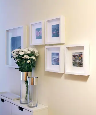 a vase with white flowers on a wall with pictures at OPO Trinta e um in Porto
