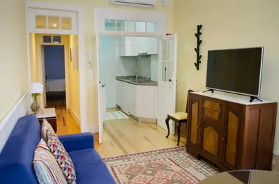 a living room with a blue couch and a flat screen tv at Porto.arte downtown apartment in Porto