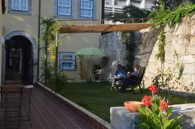 two people sitting in chairs under an umbrella in a yard at Porto.arte downtown apartment in Porto
