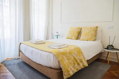 a bedroom with a bed with a yellow blanket on it at Impar Luxury Apartments in Porto