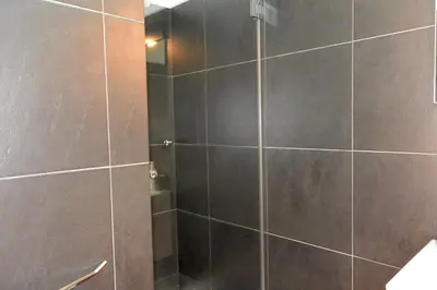 a bathroom with a shower with black tile at Júlio Dinis Flat, by Flat in Porto in Porto