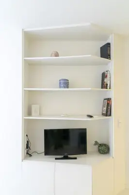 a living room with white shelves and a tv at Formosa Flats in Porto